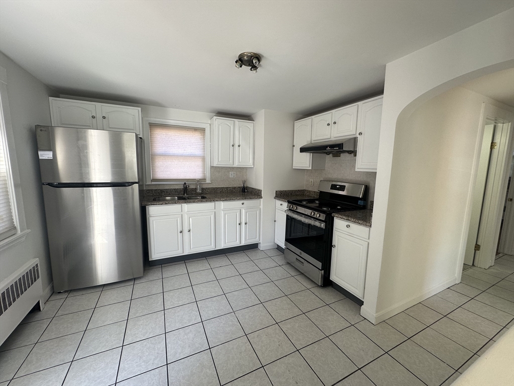 206 Adams Street, Unit 206 Newton, MA 02458 - Photo 7 of 37 a kitchen with white cabinets a sink a stove a refrigerator and a window