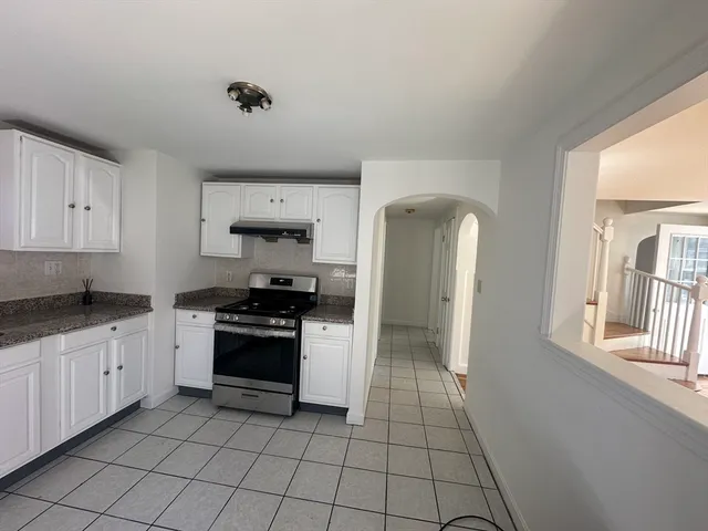 a kitchen with granite countertop a stove a sink and a refrigerator