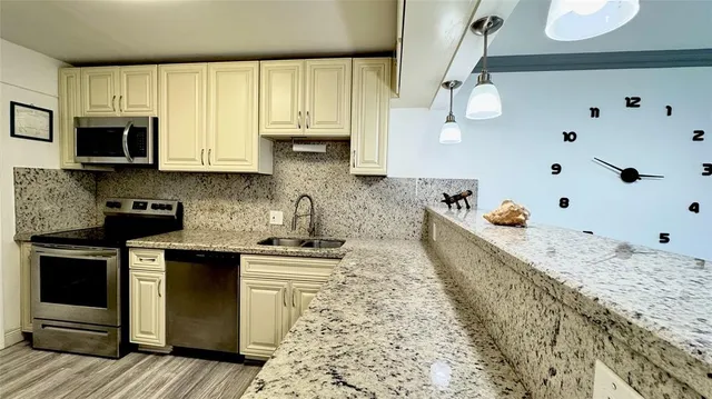 a kitchen with kitchen island granite countertop a sink a stove and cabinets