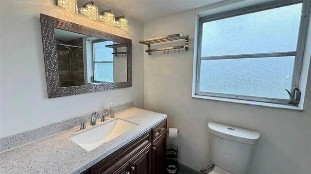a bathroom with a granite countertop sink toilet and mirror