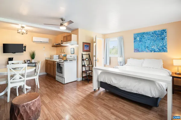 a open kitchen with stainless steel appliances granite countertop a stove top oven a sink a dining table and chairs with wooden floor