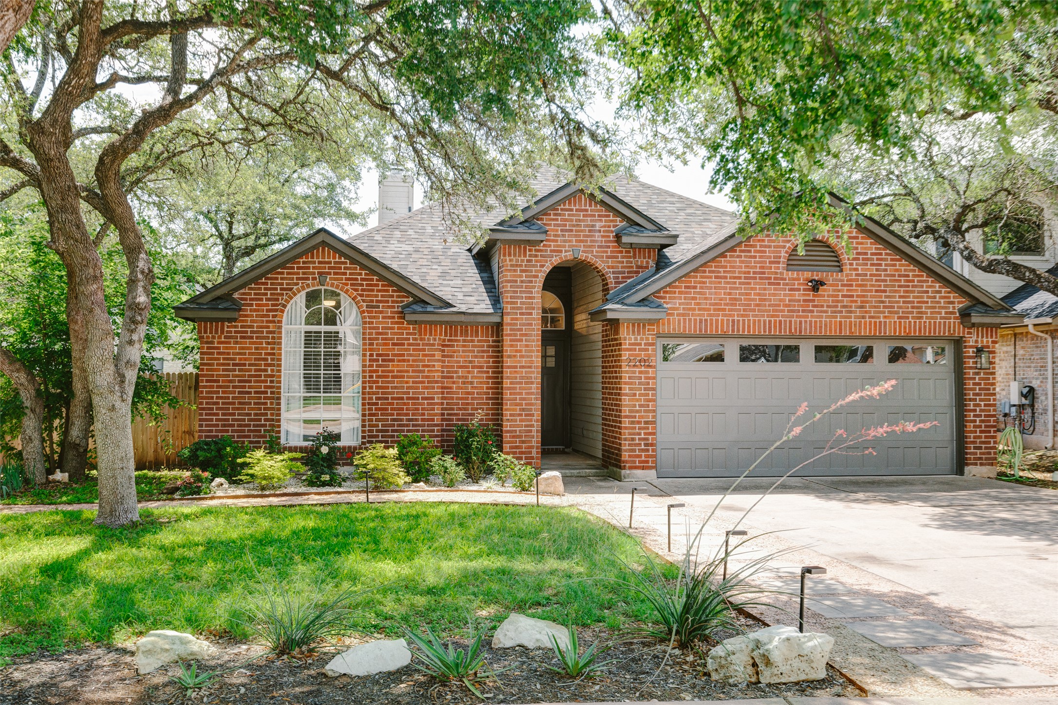 2202 Old Mill Road Cedar Park, TX 78613 - Photo 22 of 23 Mature trees frame this charming brick home with a new roof. Also featured is an arched entry and a new garage door with window inserts.