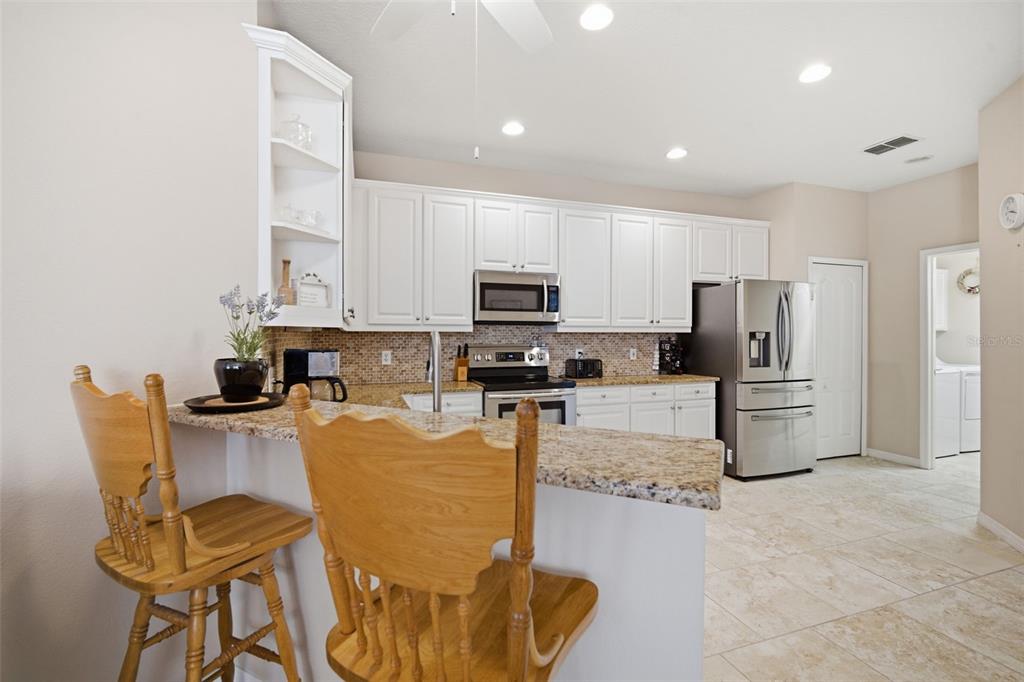 6057 Sandhill Ridge Drive Lithia, FL 33547 - Photo 16 of 83 a kitchen with stainless steel appliances granite countertop a table and chairs
