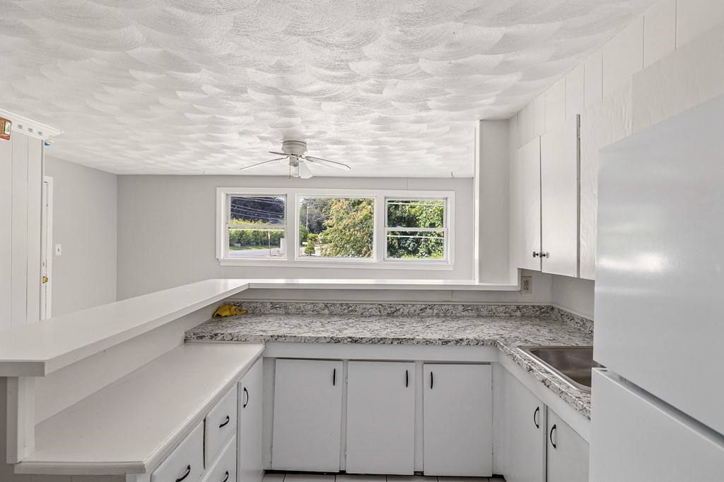 102 Mendon Street Blackstone, MA 01504 - Photo 5 of 41 a kitchen with granite countertop white cabinets and a window