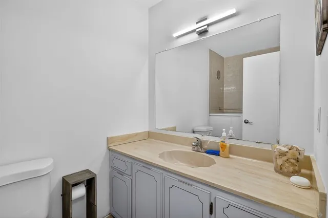 a bathroom with a granite countertop sink a toilet and mirror