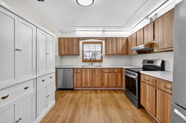 a kitchen with cabinets wooden floor and stainless steel appliances