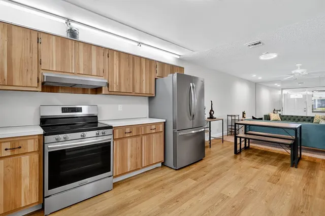 a kitchen with stainless steel appliances a stove a refrigerator and a hard wood floors