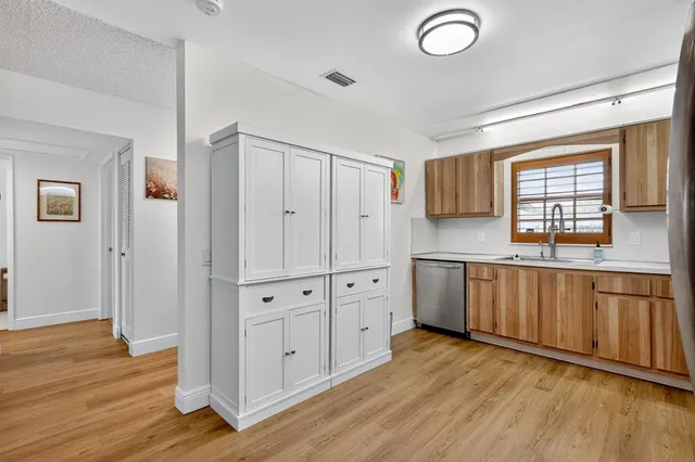 a kitchen with stainless steel appliances granite countertop a refrigerator a sink dishwasher and white cabinets with wooden floor