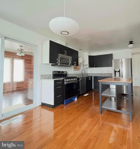a large open kitchen with stainless steel appliances granite countertop a stove top oven a sink dishwasher a dining table and chairs with wooden floor