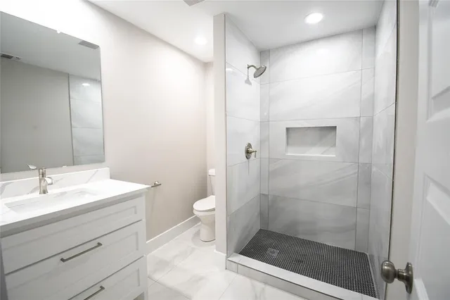 a bathroom with a shower sink vanity and toilet