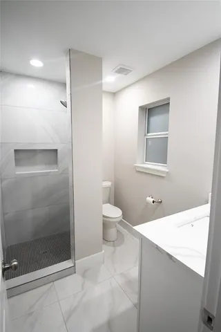 a bathroom with a granite countertop sink a toilet and shower