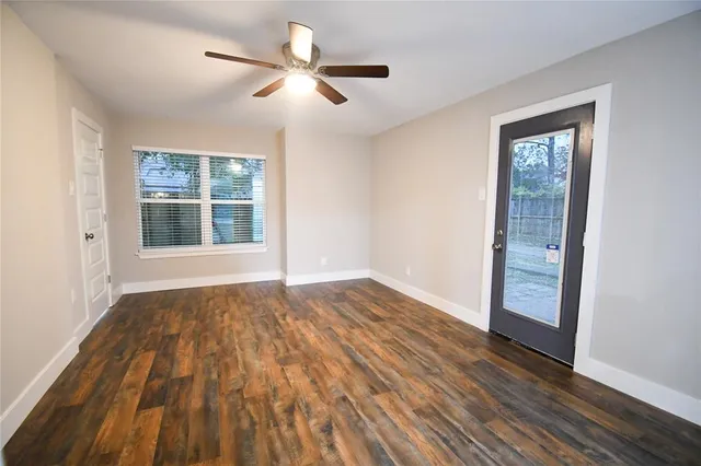a view of an empty room with wooden floor and a window