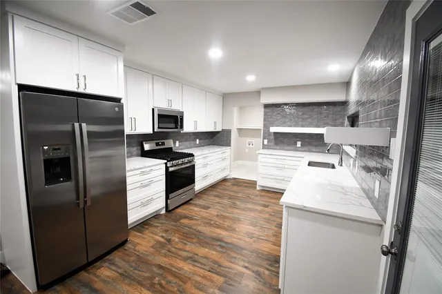 a modern kitchen with stainless steel appliances granite countertop a refrigerator a stove a sink and a microwave