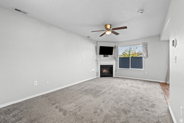 652 West 800 North, Unit 45 Clinton, UT 84015 - Photo 5 of 17 Living area featuring neutral-toned carpet, a corner fireplace with a white mantel, and a ceiling fan with integrated lighting