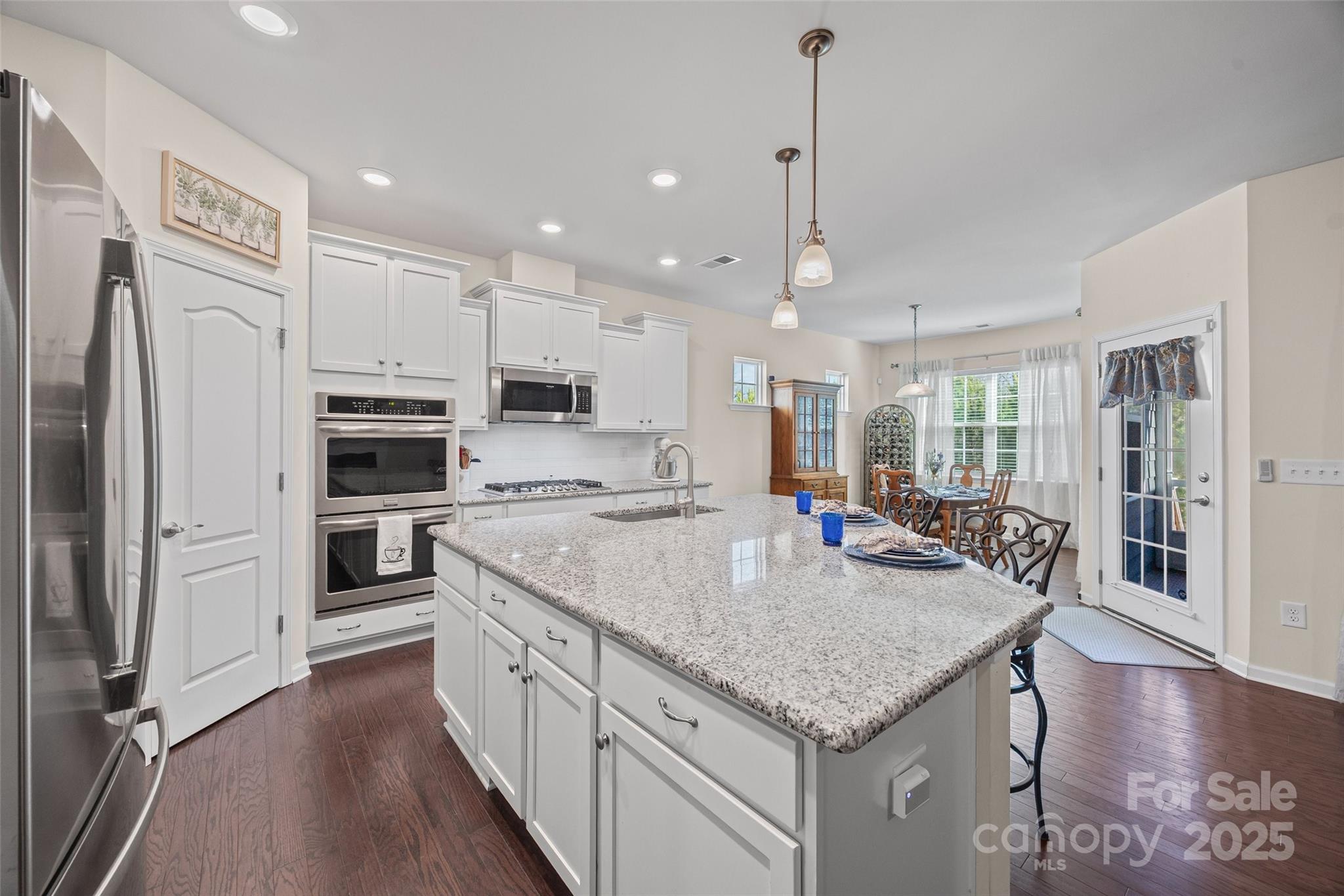1609 Tranquility Boulevard Lancaster, SC 29720 - Photo 7 of 29 a kitchen with stainless steel appliances granite countertop a kitchen island a stove a refrigerator a oven and a sink with wooden floor