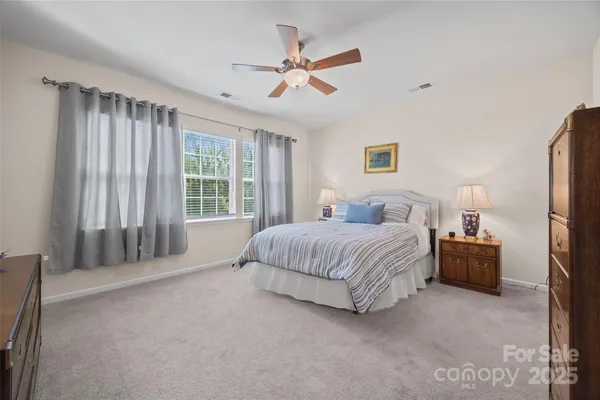a spacious bedroom with a bed painting and a large window