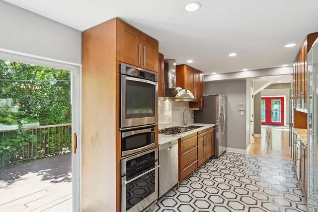 a kitchen with stainless steel appliances granite countertop a refrigerator a stove and a sink with wooden cabinets