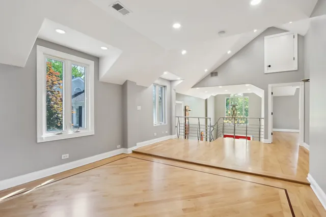a view of an empty room with wooden floor and a bathroom