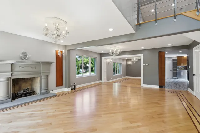 a view of an empty room with wooden floor fireplace and a window