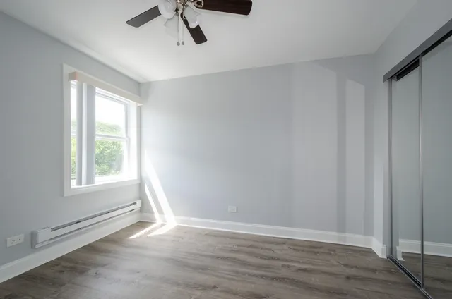 a view of an empty room with a window and hardwood floor