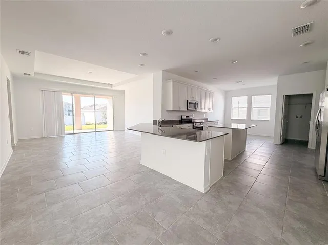 a large white kitchen with kitchen island a sink a stove a refrigerator and white cabinets