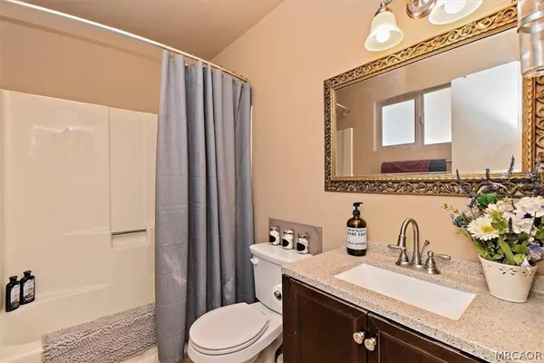 a bathroom with a granite countertop sink mirror vanity and toilet