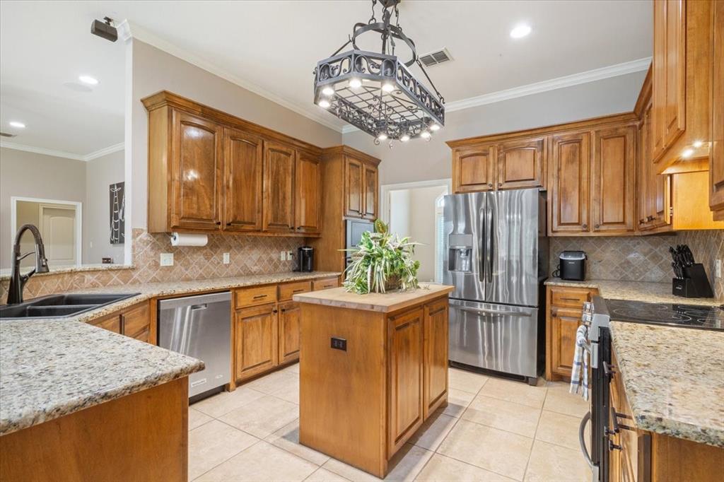 203 Silver Spur Trail Waco, TX 76657 - Photo 11 of 39 Kitchen with crown molding, stainless steel appliances, light tile patterned floors, backsplash, and recessed lighting