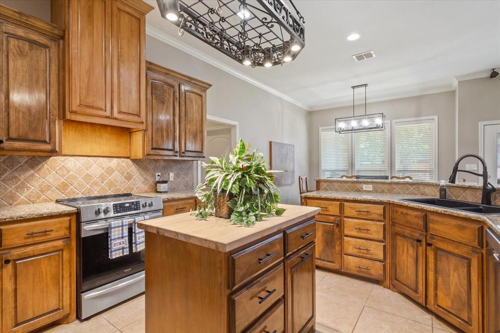 203 Silver Spur Trail Waco, TX 76657 - Photo 13 of 39 Kitchen featuring backsplash, stainless steel range with electric stovetop, butcher block countertops, light tile patterned floors, and crown molding