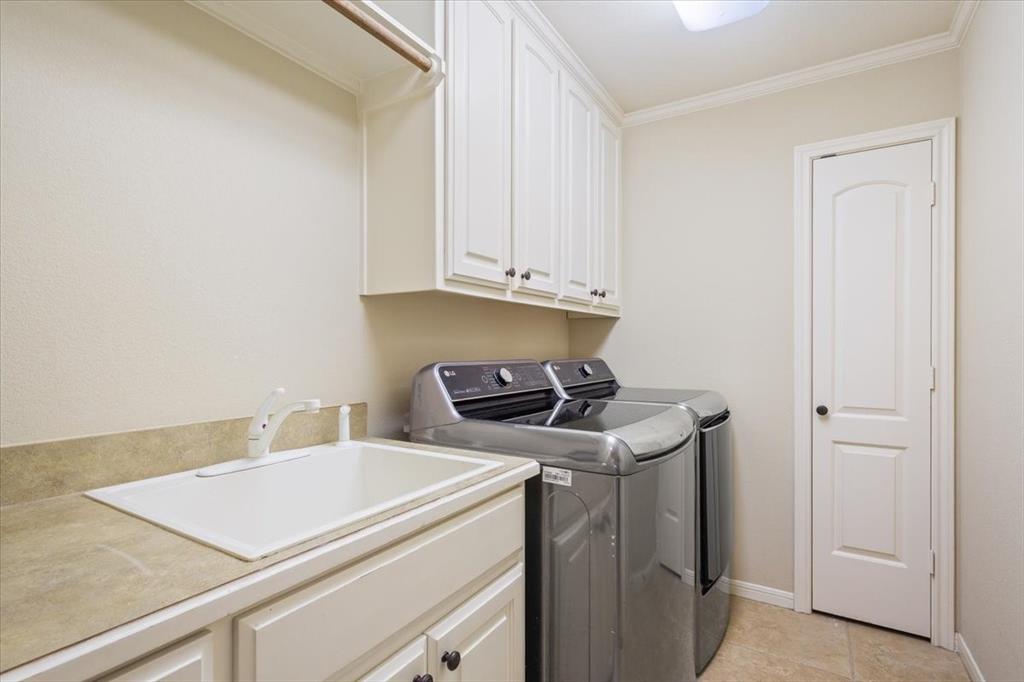 203 Silver Spur Trail Waco, TX 76657 - Photo 26 of 39 Washroom featuring separate washer and dryer, cabinet space, crown molding, and light tile patterned flooring