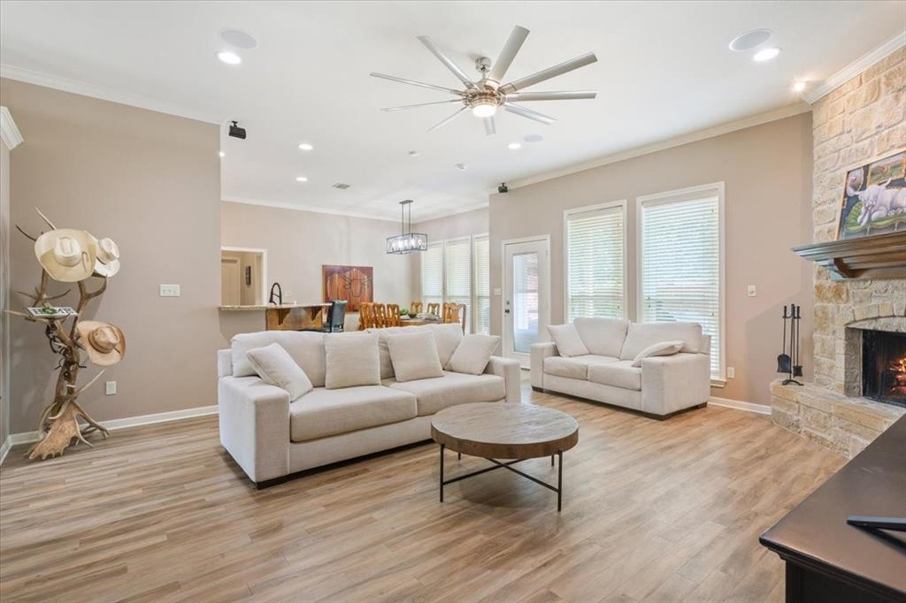 203 Silver Spur Trail Waco, TX 76657 - Photo 9 of 39 Living room featuring crown molding, light wood-style flooring, ceiling fan, recessed lighting, and a stone fireplace