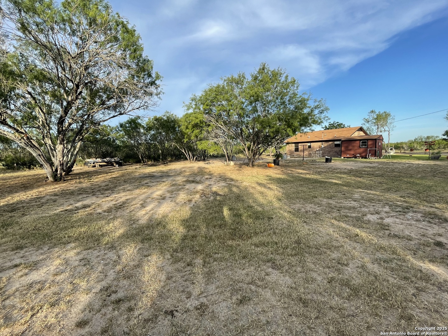 311 3rd Street Christine, TX 78012 - Photo 10 of 10 a backyard of a house with table and chairs under an umbrella