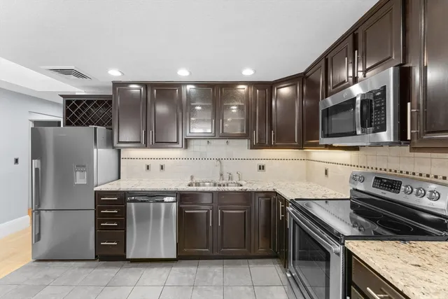 a kitchen with stainless steel appliances granite countertop a stove a sink and a microwave