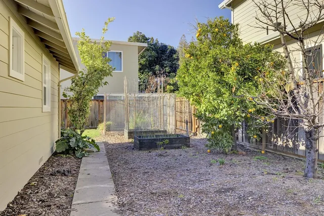 a view of backyard of house with wooden fence