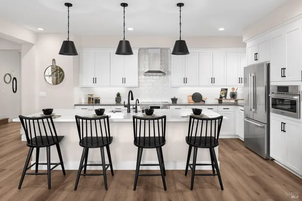 a kitchen with stainless steel appliances a dining table chairs and a wooden floor
