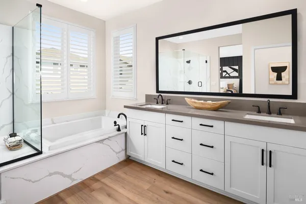 a spacious bathroom with a double vanity sink a mirror and a bathtub