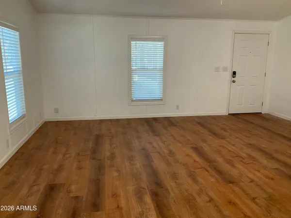 a view of an empty room with wooden floor and a window