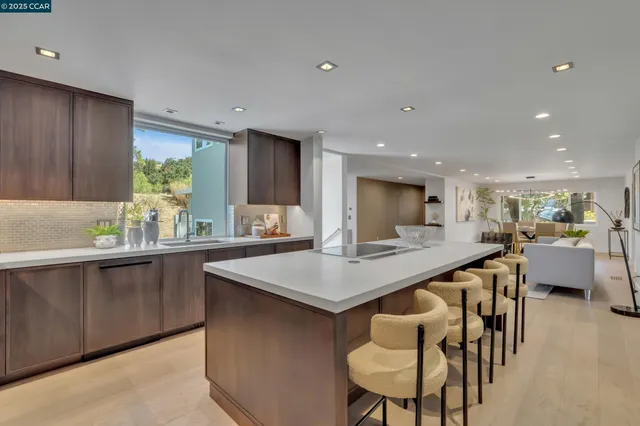 a kitchen with stainless steel appliances kitchen island a table chairs sink and refrigerator