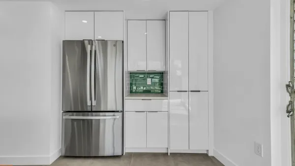 a view of kitchen with granite countertop cabinets and refrigerator
