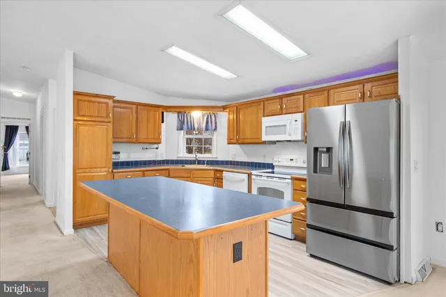 a kitchen with stainless steel appliances granite countertop a refrigerator a sink and a stove