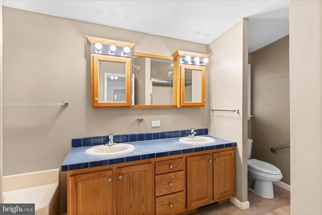 a bathroom with a granite countertop sink toilet and mirror