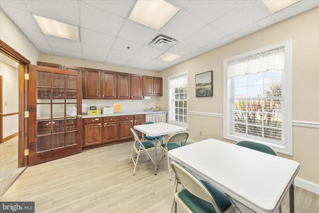 a room with stainless steel appliances kitchen island granite countertop a table chairs sink and cabinets