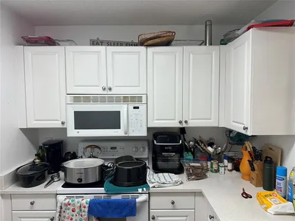 a kitchen with stainless steel appliances a stove a sink and white cabinets