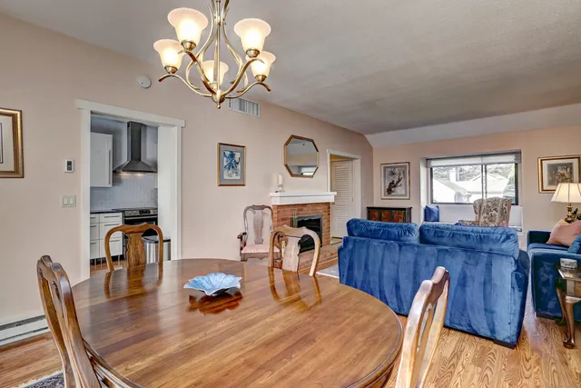 a dining room with wooden floor a chandelier a wooden table and chairs