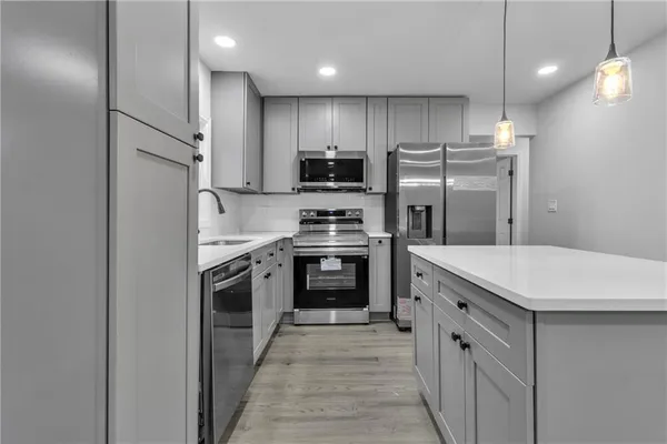 a kitchen with kitchen island a stove top oven and refrigerator