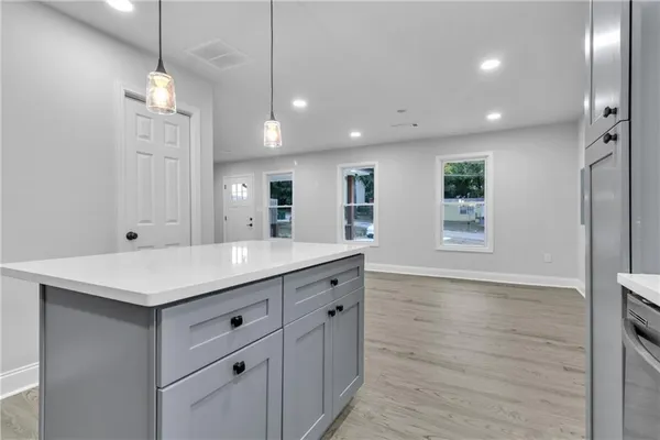 a kitchen with a sink chandelier and wooden floor