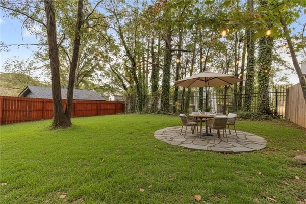 a backyard of a house with large trees and wooden fence