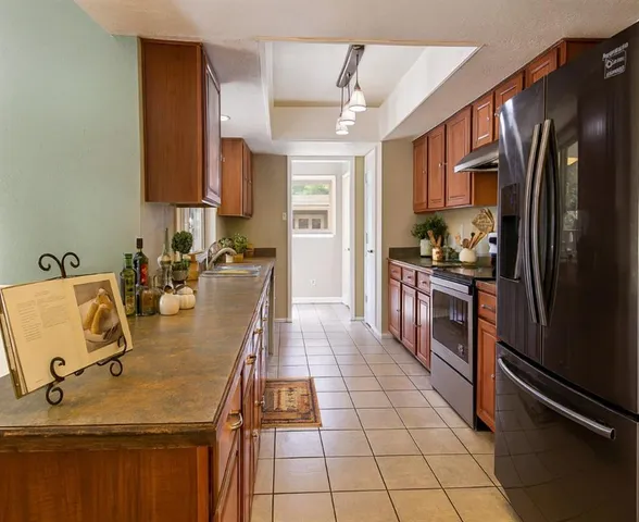 a kitchen with stainless steel appliances granite countertop a sink refrigerator and cabinets