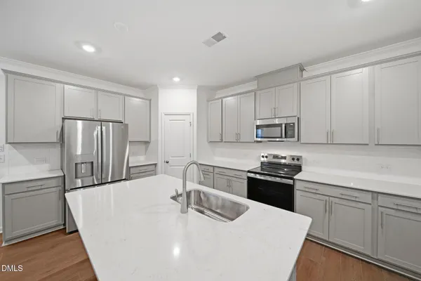 a kitchen with stainless steel appliances a sink a stove a refrigerator with white cabinets