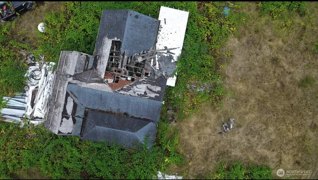 an aerial view of a house with outdoor space and trees all around