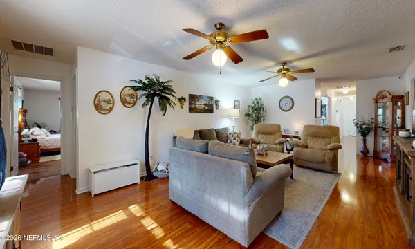 a living room with couches and kitchen view with wooden floor